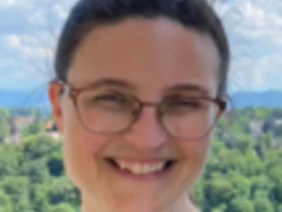 Kay Orzech smiles before a faraway view of green forests and mountains. 